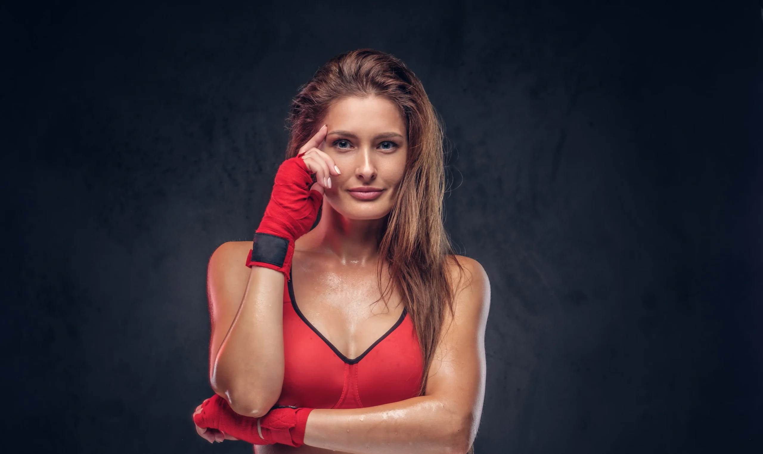 atractiva-morena-con-guantes-rojos-y-sosten-deportivo-posa-para-el-fotografo-en-el-estudio